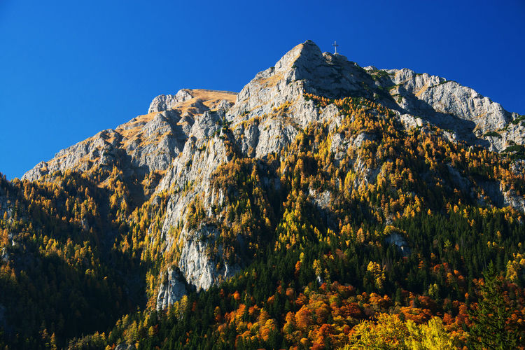 Low angle view of cross on bucegi mountains against clear blue sky