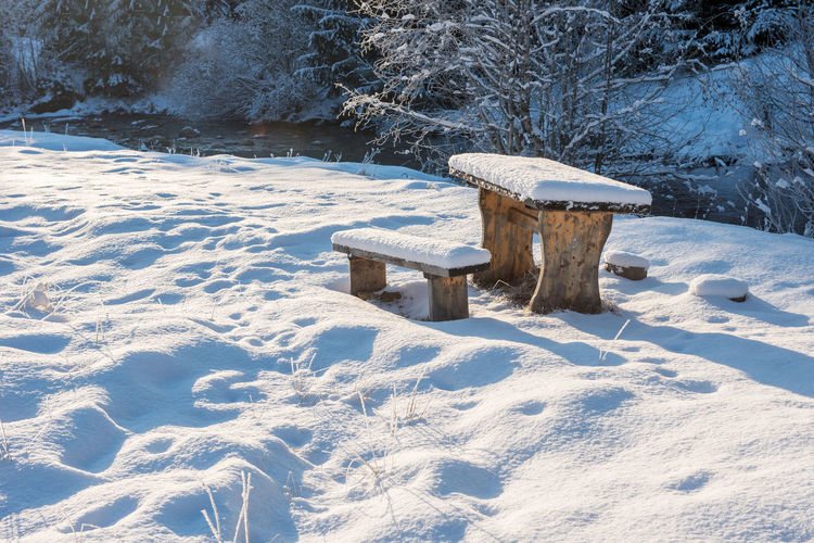 Snow covered bench on field during winter
