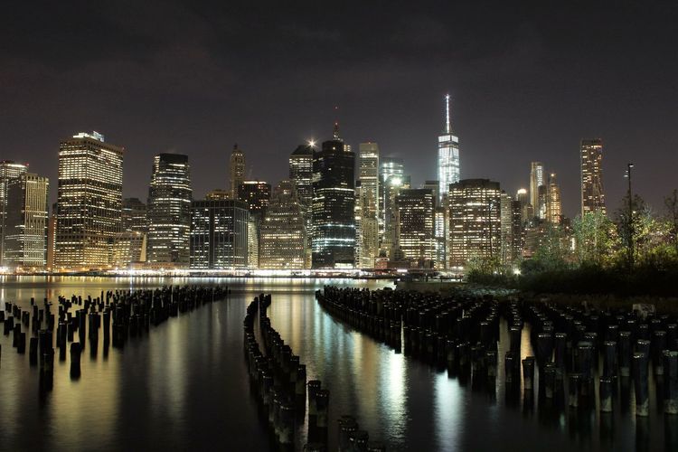 Scenic view of river by illuminated cityscape at night
