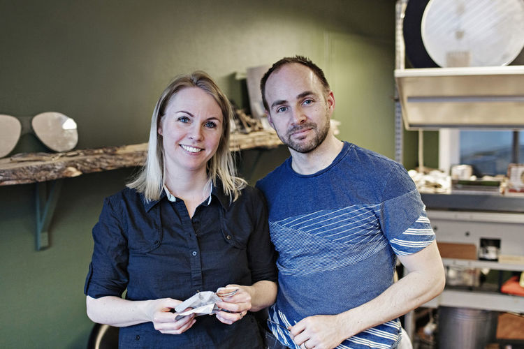 Portrait of confident couple standing in eyeglasses workshop