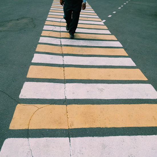 Low section of man walking on zebra crossing