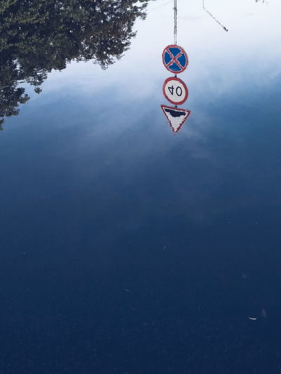 High angle view of sign hanging by lake against sky