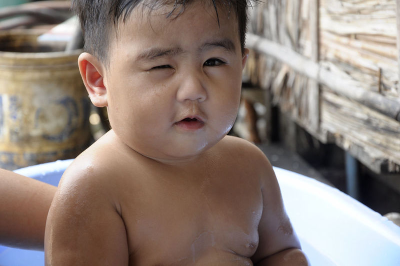 Portrait of shirtless cute baby boy winking eye