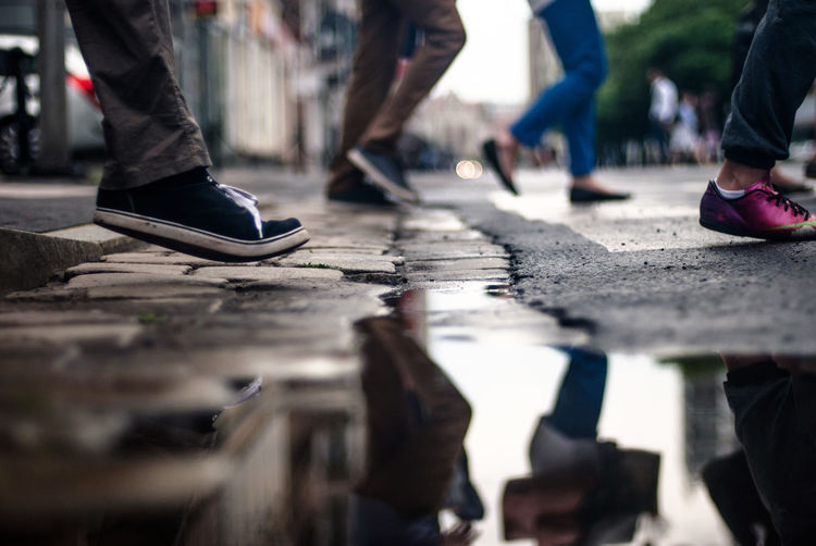 Low section of people walking by puddle