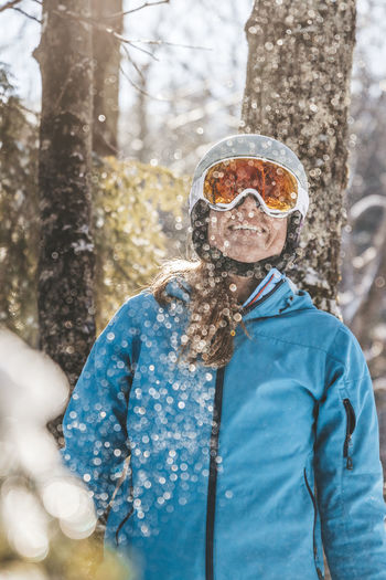 Woman in ski goggles and helmet in backlit snow scene in new hampshire