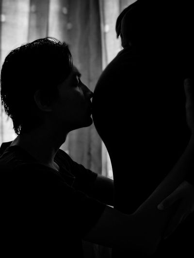 Side view of man kissing the pregnant belly