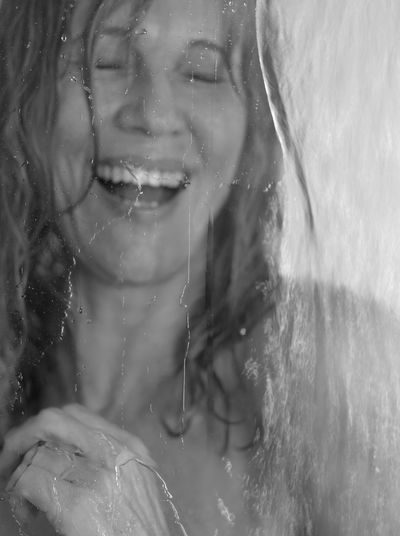 Close-up of mature woman taking bath seen through window