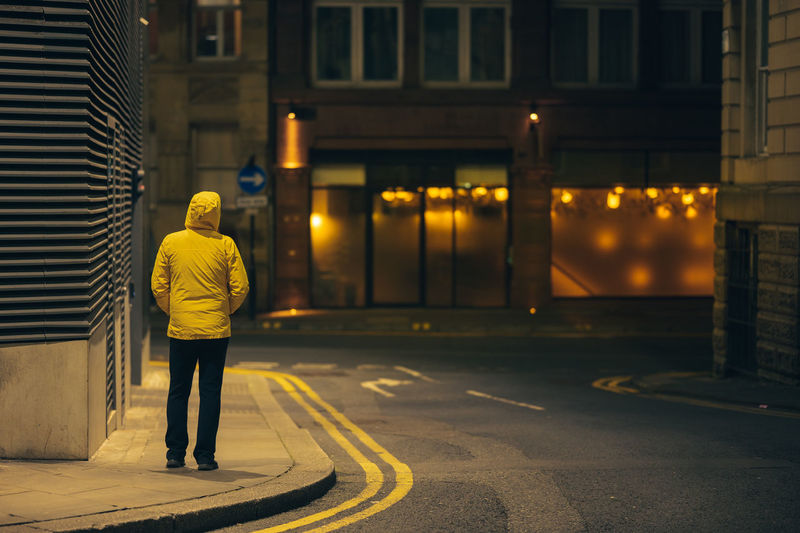 Rear view of man walking on street in city
