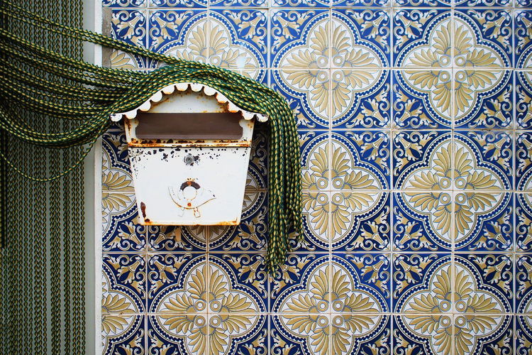 Beaded curtain on rusty mailbox over wall