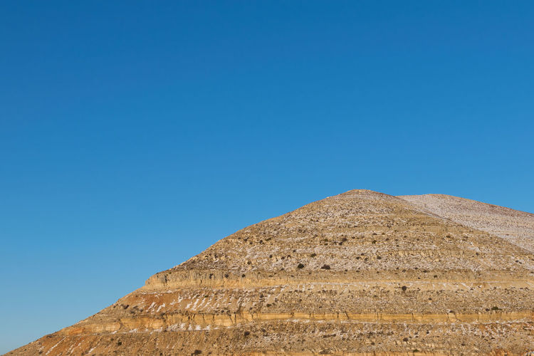 Low angle view of historical egyptian pyramid against blue sky
