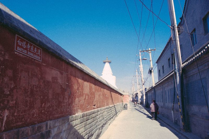 View of miaoying temple behind wall against sky