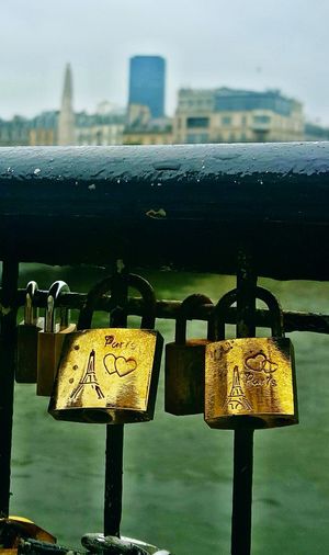 Close-up of padlocks hanging on railing by river in city