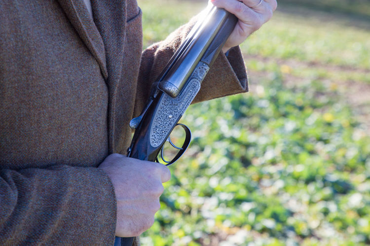 Man holding a shotgun whilst out pheasant shooting.