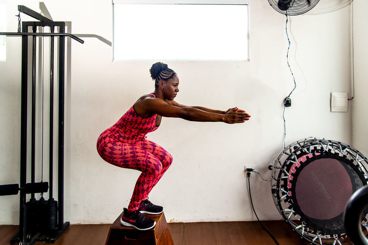 Determined woman doing squat exercises with arms out in front. body strengthening.