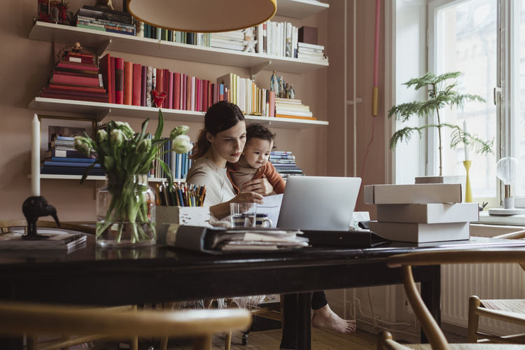 Female entrepreneur with toddler son working in home office