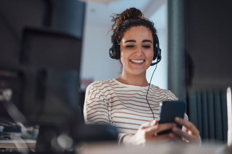 Happy businesswoman with headset using mobile phone in office