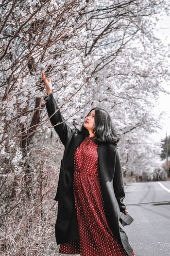 Full length of woman standing on snow covered tree