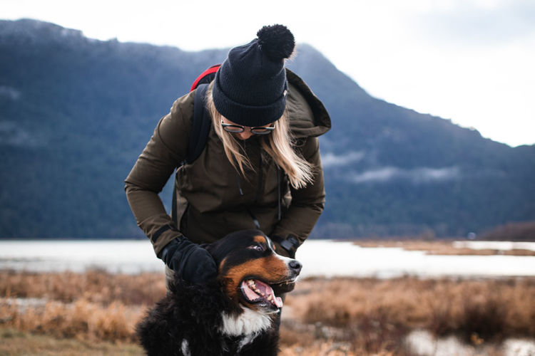 Woman standing with dog against mountain during winter