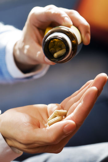 Cropped hand of person taking capsules