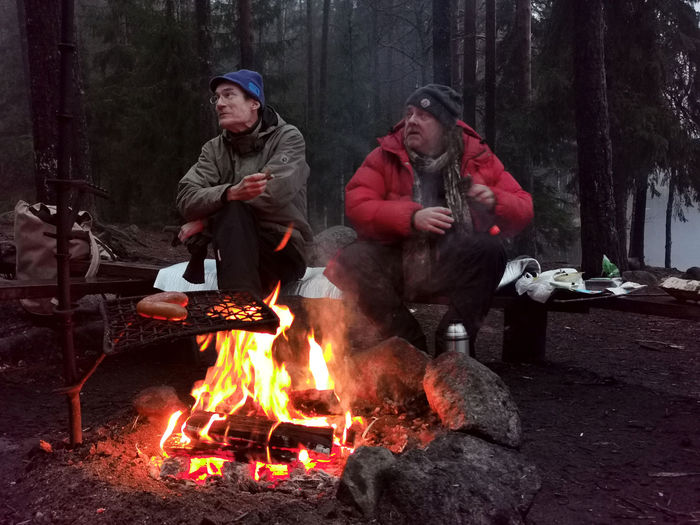 People sitting on bonfire in forest during winter