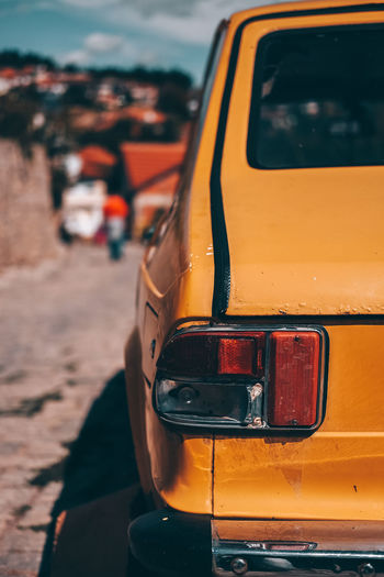 Close-up of yellow car on road