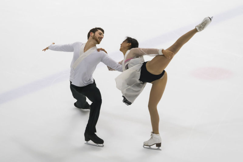 Man and woman performing during figure skating against white background