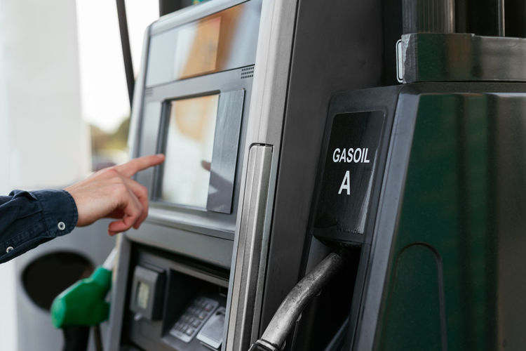 Cropped unrecognizable person paying with card at machine in modern petrol station