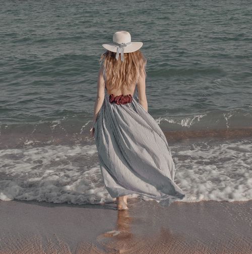 Rear view of woman with hat on beach