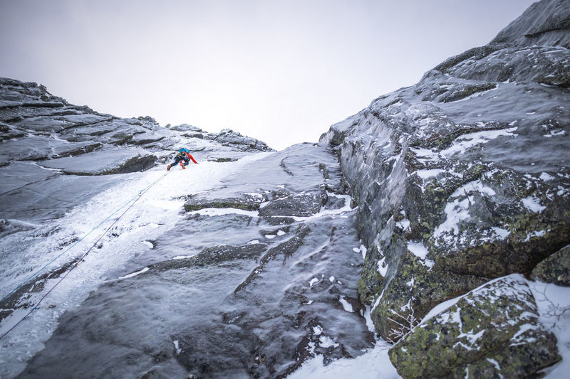 An alpine ice climber climbing a steep section on a large mountain