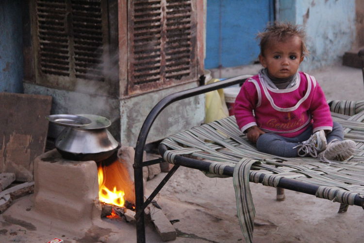 Close-up of boy sitting on cot by fireplace