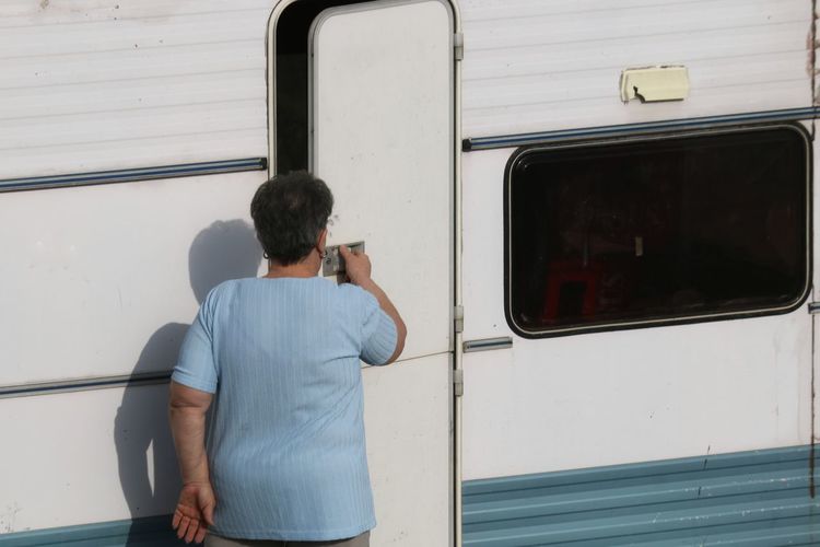 Rear view of woman opening door of camper trailer