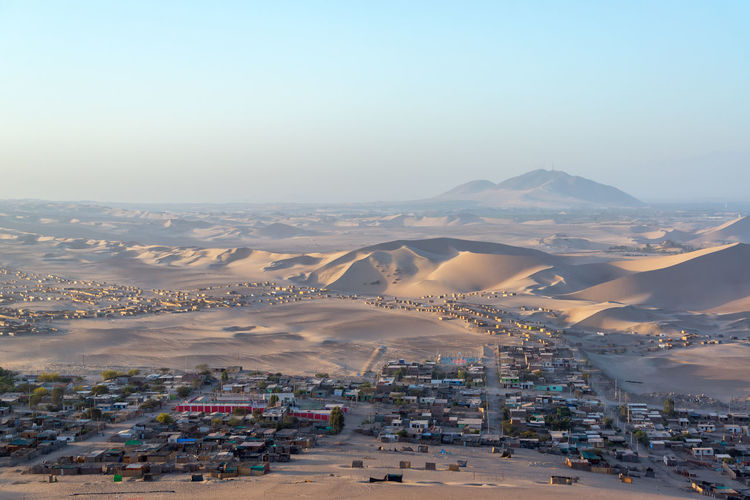 Village in desert against clear sky at huacachina