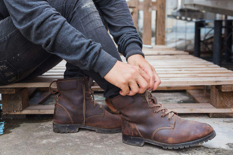 Low section of man tying shoelace while sitting on palette