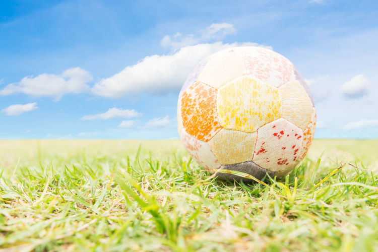 Close-up of soccer ball on field against sky