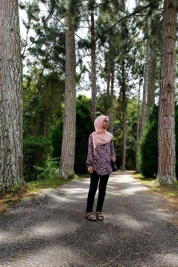 Full length of woman walking on road amidst trees
