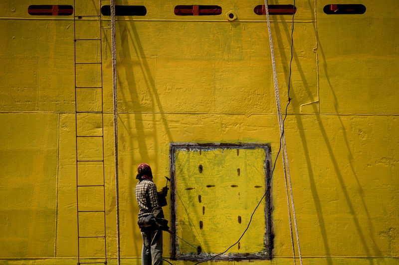 Rear view of worker painting wall outdoors