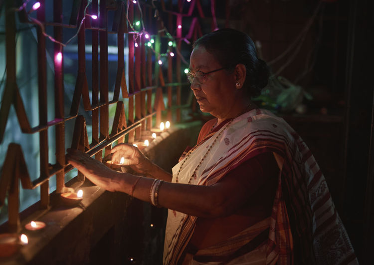 A hindu woman decorating her home with diyas on the evening of diwali and kali puja.