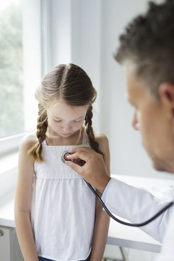 Doctor wearing mask examining girl in clinic