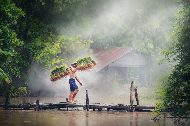 Farmer carrying crop while walking on pier over lake