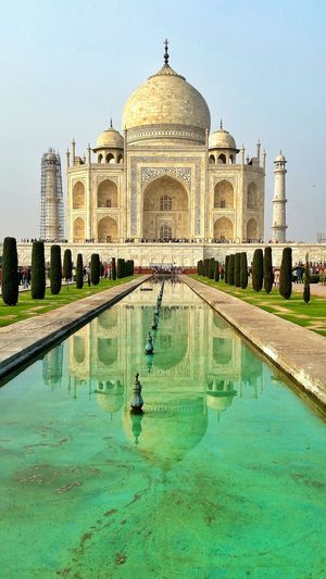 Low angle view of taj mahal in front of pond against sky