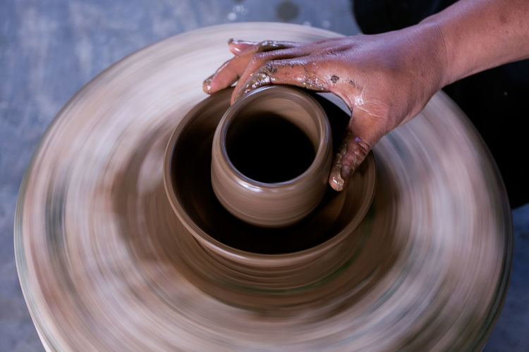 Cropped hand of potter making pot at workshop