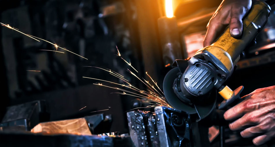 Worker cutting metal with power tool at workshop