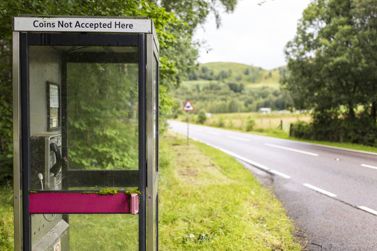 Telephone booth on field by road