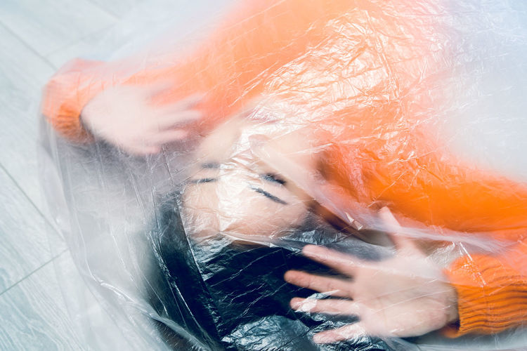 Teenage girl wrapped in plastic on floor