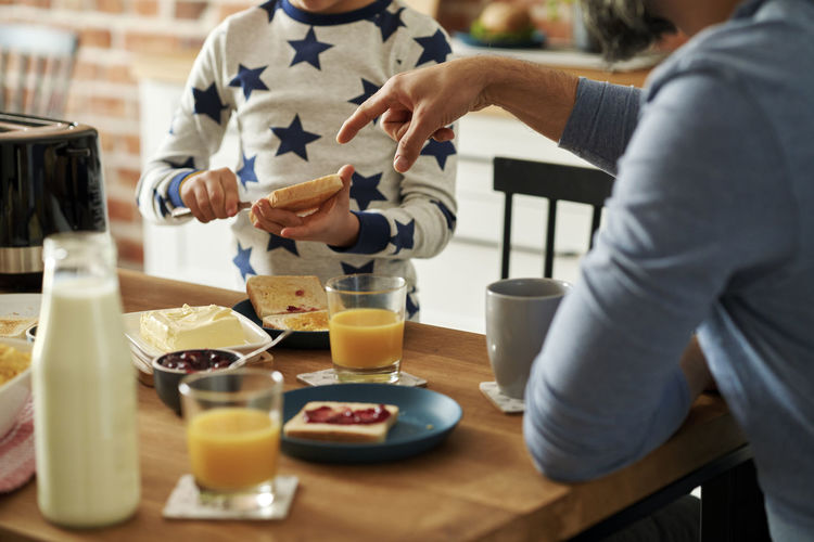 Midsection of man with son having breakfast at table