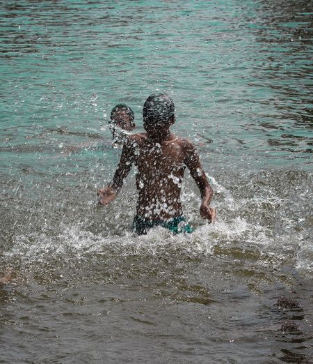 Full length of shirtless man splashing water