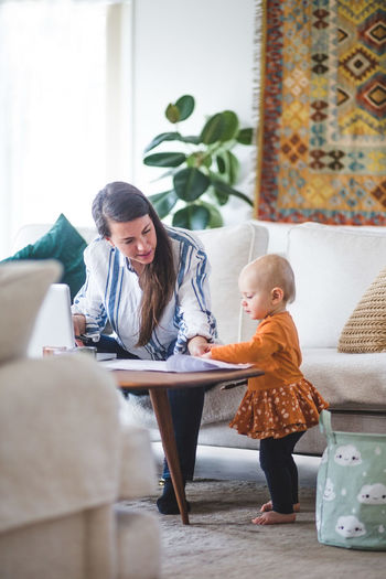 Working mother talking with loving daughter while managing her business from home office