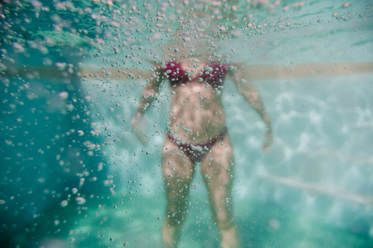 Mid adult woman wearing bikini swimming in pool