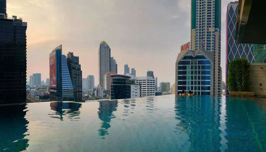 Modern buildings by swimming pool in city against sky