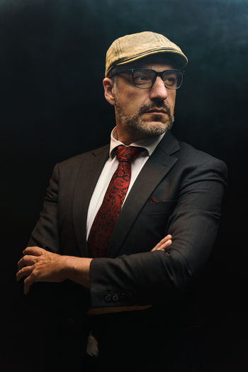 Portrait of businessman standing against black background